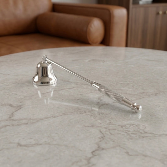 Silver candle snuffer on a marble surface with a blurred background